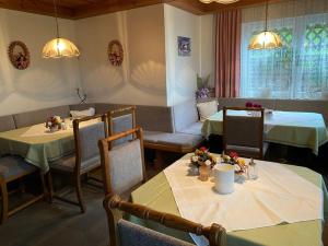 un comedor con 2 mesas y sillas, una mesa y un sillón en Gästehaus Lisbeth, en Bad Kleinkirchheim