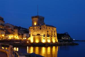 an old building with lights on the water at night at Attic Apartment in Rapallo