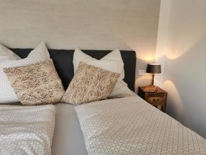 ein Bett mit weißer Bettwäsche und Kissen darauf in der Unterkunft Heeser Hof - Urlaub im Grünen in Weeze