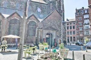 un grand bâtiment avec des personnes assises à table devant lui dans l'établissement Studio donceel, à Liège