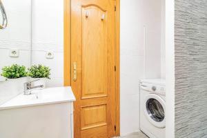 łazienka z pralką i drewnianymi drzwiami w obiekcie Encantador Apartamento en Chueca junto a Gran Vía, Infantas 1-1 by Batuecas w Madrycie +3 zdjęcia