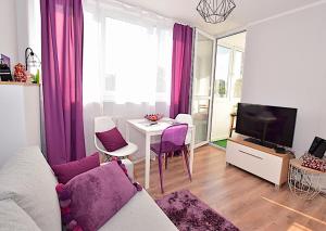 salon z kanapą i stołem z fioletowymi krzesłami w obiekcie Apartament nad Strugą w Toruniu