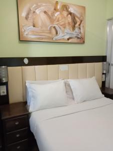 a bed with white sheets and pillows and a painting on the wall at Faria Guimares Porto Centro - Rooms & Cosy Apartments in Porto