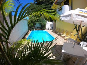 a swimming pool in a yard with chairs and an umbrella at Aguamarinha Pousada in Porto De Galinhas