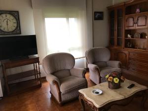 sala de estar con 2 sillas, mesa y TV en Casa Hipólito en A Estrada