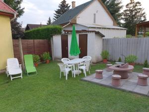 podwórko ze stołem, krzesłami i zielonym parasolem w obiekcie Crystal Sóstó Apartman w Nyíregyházie