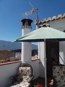 uma mesa e cadeiras com um guarda-sol e um farol em Casa Santa Ana em Lanjarón