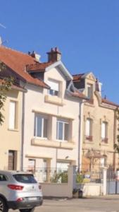 a white house with a car parked in front of it at joli studio au coeur de Verdun in Verdun