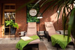a group of chairs and a clock on a brick wall at Heide Hotel Reinstorf in Reinstorf