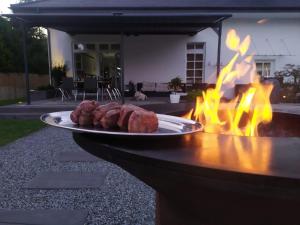 a plate of meat on a table in front of a fire at House-Cora in Stare Miasto