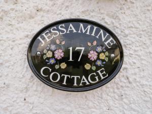 a sign on a wall with flowers on it at Jessamine Cottage in Lydbrook