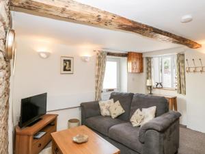 a living room with a couch and a tv at Jessamine Cottage in Lydbrook