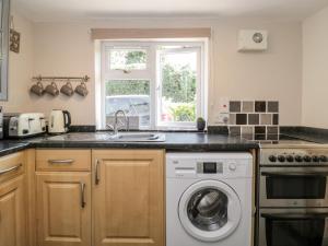 a kitchen with a sink and a washing machine at Jessamine Cottage in Lydbrook