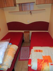 two beds in a small room with red sheets at Le Vert Océan in Talmont