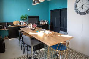 a large wooden table in a kitchen with a clock on the wall at Hotel Galla Placidia in Narbonne