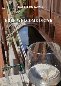 una copa de vino sentada en una cornisa frente a un canal en Balcone sul canale, en Venecia