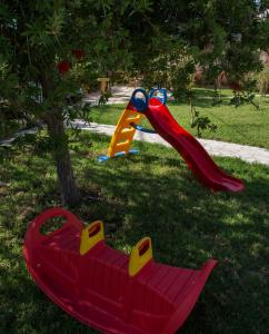 un parque infantil con un tobogán y un banco rojo en Dimas V House, en Parga
