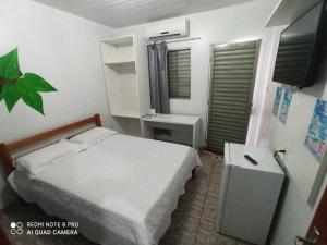 a bedroom with a bed and a table and a window at Pousada Sorriso da Mata.. in Alter do Chao