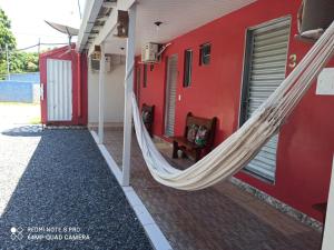 a red house with a hammock in front of it at Pousada Sorriso da Mata.. in Alter do Chao