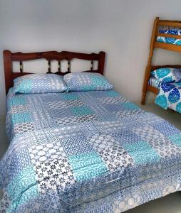a bed with a blue and white quilt on it at Recanto da Nice in Paraty