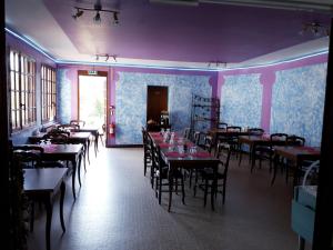 a dining room with tables and chairs and purple walls at Hôtel Le Verseau in Boulleret