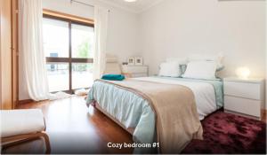 a white bedroom with a bed and a large window at Midway to Geres and Braga in Amares