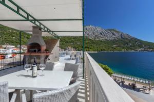 a table with wine glasses on a balcony with a view of the ocean at Dado A4 Studio Apartments in Igrane