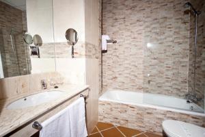 a bathroom with a tub and a sink and a toilet at Hotel Albaida Nature in Mazagón