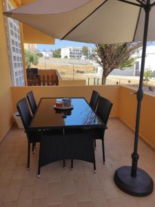 uma mesa e cadeiras com um guarda-sol em um pátio em Sunshine Apartment em Tavira