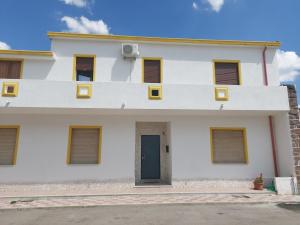 Casa blanca con ventanas amarillas y puerta en Le rondini, en Benetutti