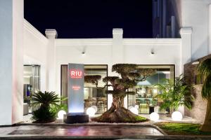 a large palm tree in front of a large building at Hotel Riu Chiclana - All Inclusive in Chiclana de la Frontera
