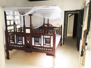 un letto in legno con baldacchino in una stanza di Furaha House a Shela