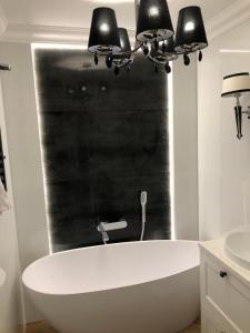 eine weiße Badewanne im Bad mit zwei Leuchten in der Unterkunft Apartament Primavera z sauną in Kielce