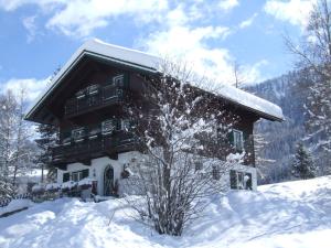 una baita di tronchi nella neve con un albero di Landhaus Kaulfuss a Sankt Jakob in Defereggen