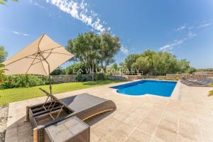 eine Terrasse mit einem Stuhl, einem Sonnenschirm und einem Pool in der Unterkunft Villa Mala Bay in Maó