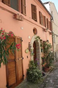 un edificio rosa con porta ad arco e fiori di B&B MAMMA ARI a Fermo