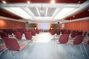 une salle de conférence avec des chaises rouges et un écran dans l'établissement Auberge de Jeunesse HI Strasbourg 2 Rives, à Strasbourg