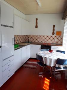 una cocina con armarios blancos y una mesa con sillas. en Casa Romana, en Someo