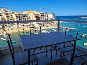 een tafel op een balkon met uitzicht op een haven bij St Julians Bay Sea Front Apartments in St Julian's