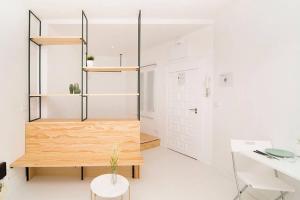 una stanza con pareti bianche, una scrivania e uno scaffale di legno di Loft de Diseño en Pleno Centro de Madrid, Calle Torrecilla del Leal, by Batuecas a Madrid