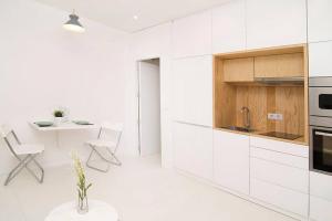 una cucina con mobili bianchi, tavolo e sedie di Loft de Diseño en Pleno Centro de Madrid, Calle Torrecilla del Leal, by Batuecas a Madrid Altre 3 foto