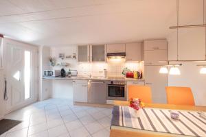 a kitchen with white cabinets and a table with orange chairs at FeWo Kleine Insel in Bad Segeberg +20 photos