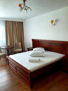 een slaapkamer met een groot bed met witte lakens bij Hotel Restaurant Elite in Drobeta-Turnu Severin
