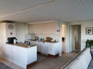 una cocina con armarios blancos y un sofá en una habitación en Full Ocean View & Game Rooms, en Hadsund