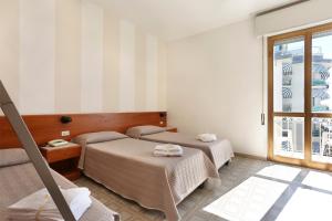 a hotel room with two beds and a window at Hotel Brunella in Lido di Camaiore