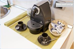 a coffee maker on a counter with cups and spoons at Room Touch And Go in Bologna