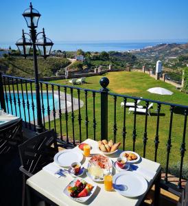 a table with plates of food on top of a balcony at Hacienda Vistamar in Frigiliana