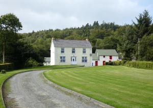 a white house with a grassy field next to a road at Alcorn's Farmhouse in Rathmullan