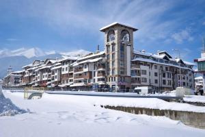 a building with a clock tower in the snow at Апартамент в комплекс Bansko Royal Towers in Bansko