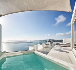 a swimming pool on the roof of a house with the ocean at Alti Santorini Suites - Caldera View in Megalokhori